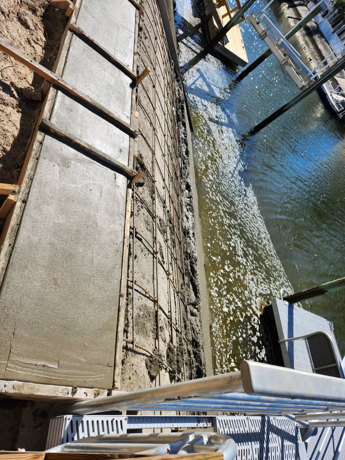 A concrete walkway is being built next to a body of water.