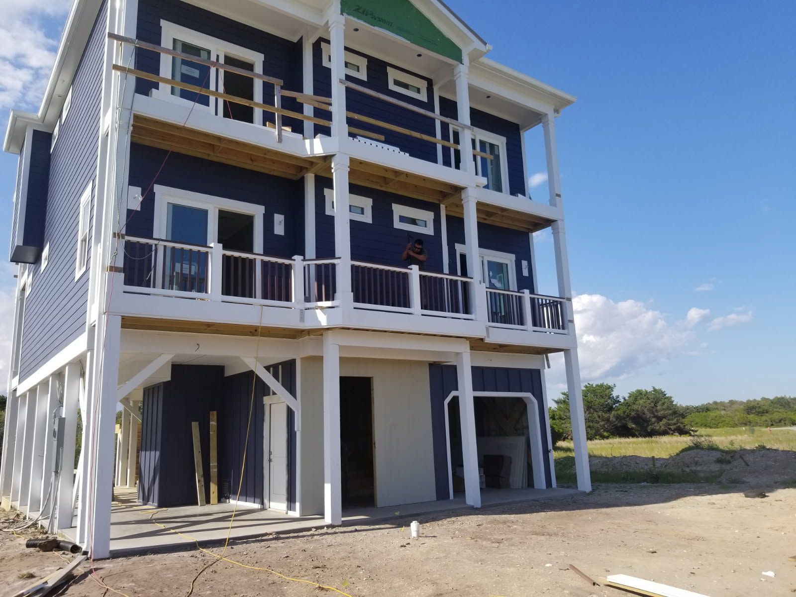 A blue and white house with a green roof is under construction
