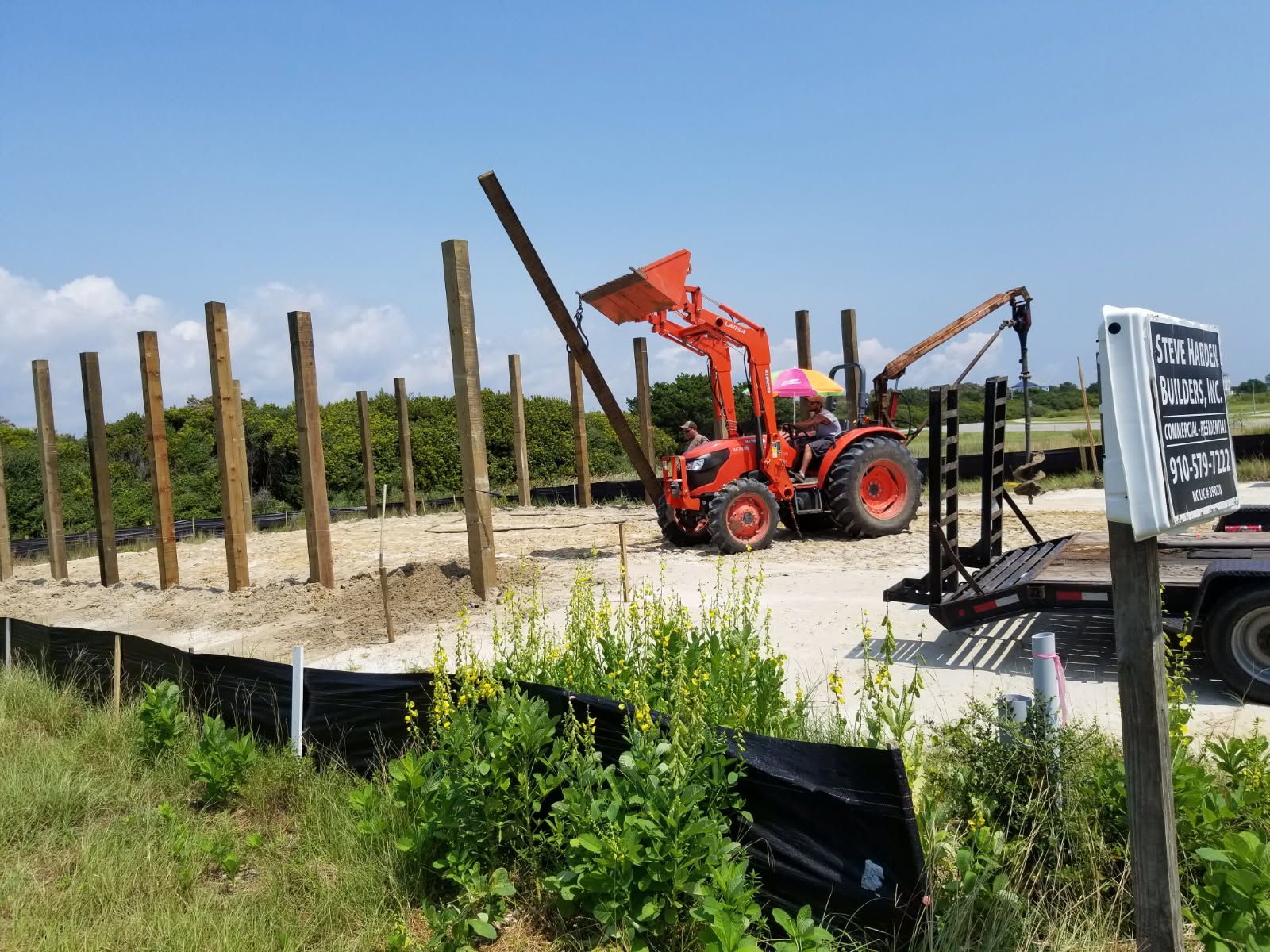A tractor is working on a wooden fence in a field.