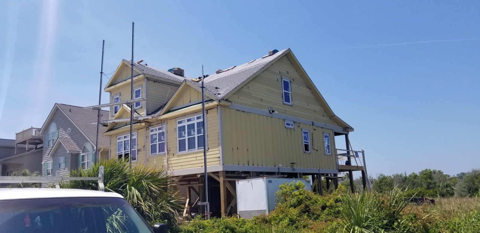 A large yellow house with a car parked in front of it.
