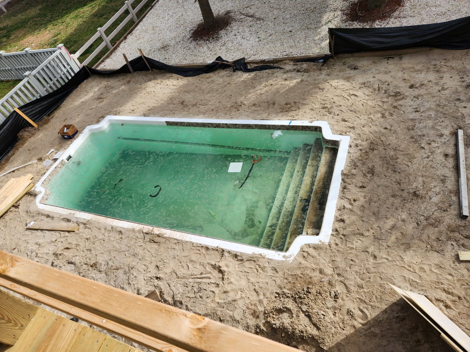 A swimming pool is being built in the backyard of a house.