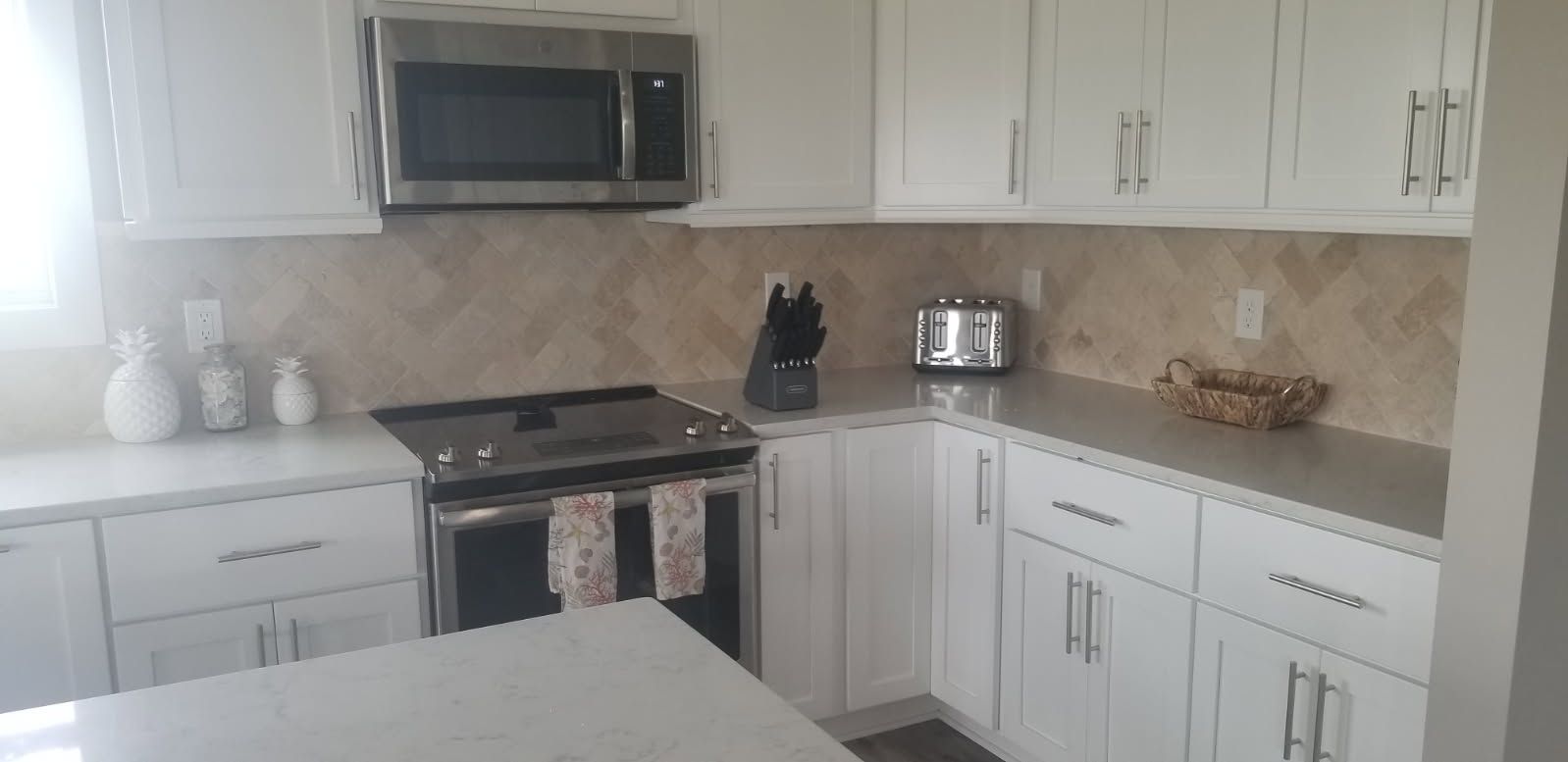 A kitchen with white cabinets , stainless steel appliances , and granite counter tops.