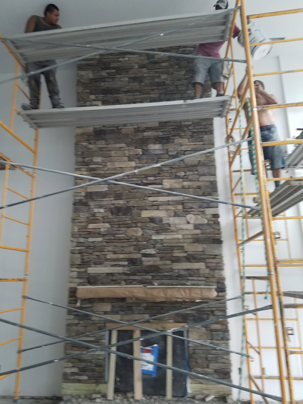 A group of construction workers are working on a stone fireplace.