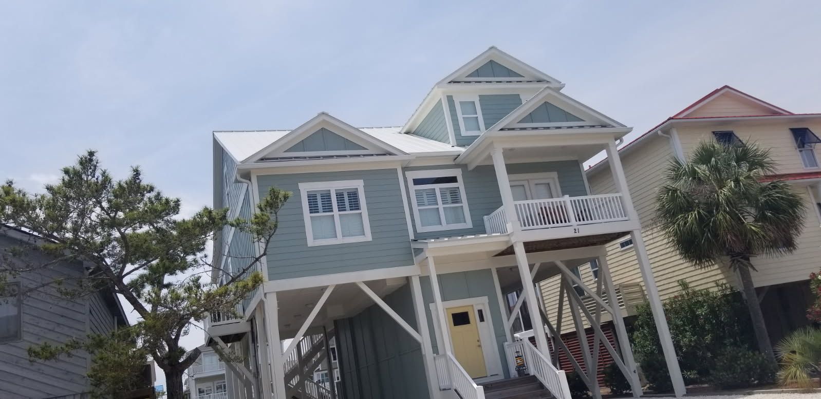 A large blue house with a white roof is sitting on top of a hill.