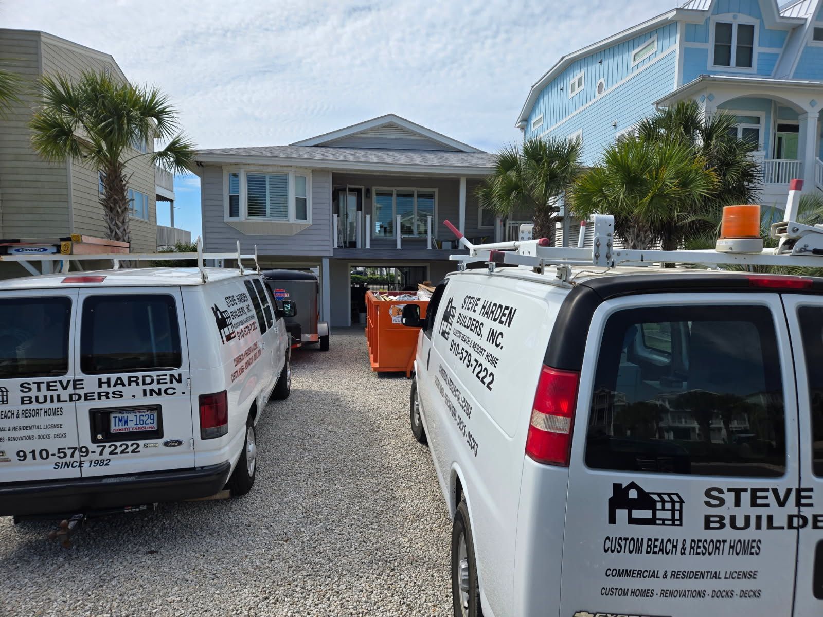 Two steve harder vans are parked in front of a house.