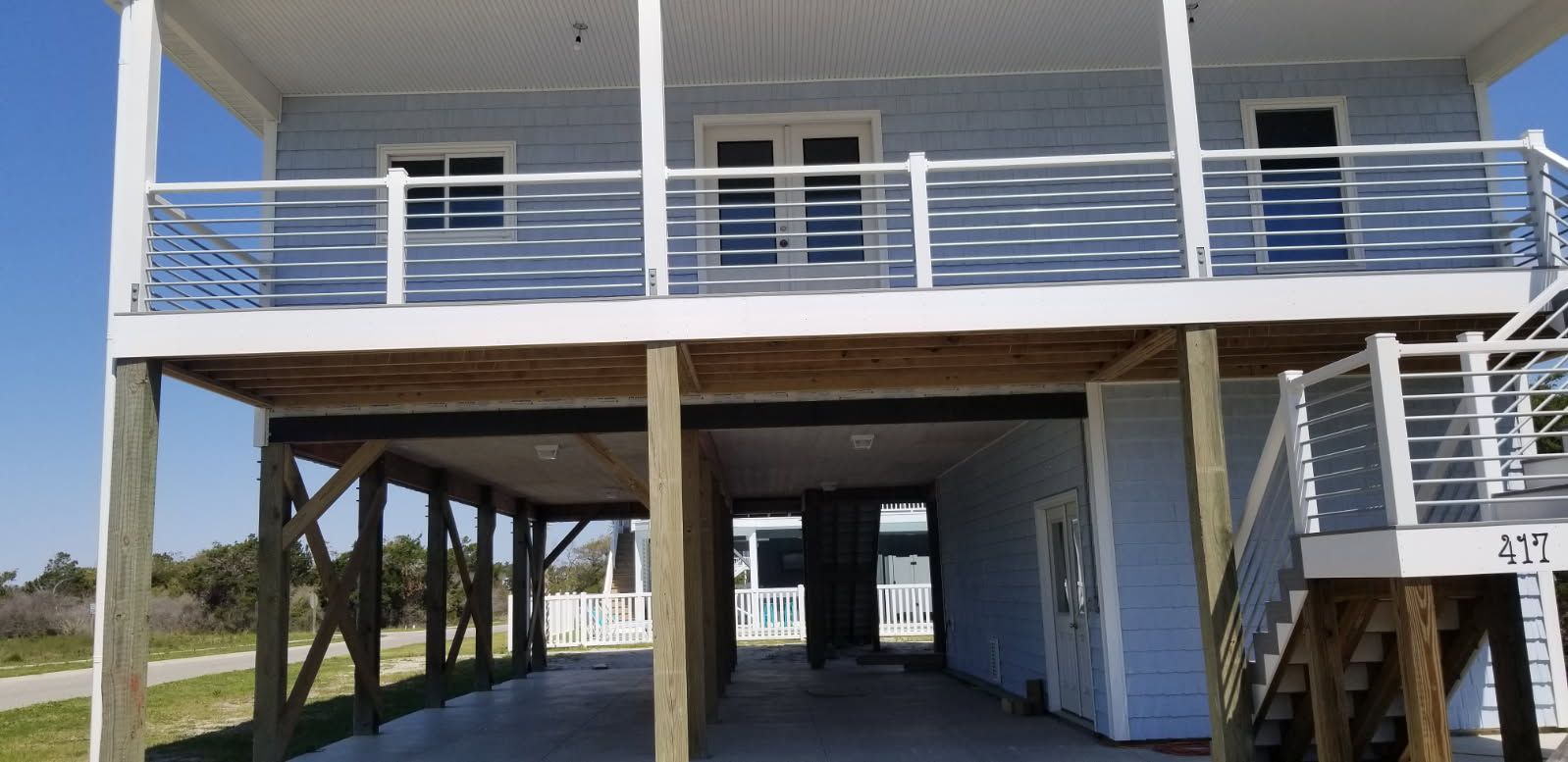 A blue house with a balcony and a carport underneath it.