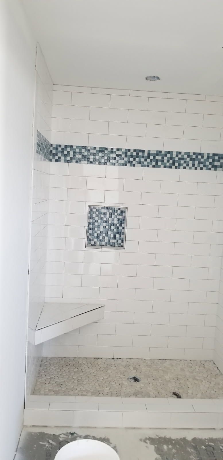 A bathroom with a shower stall and a bench.