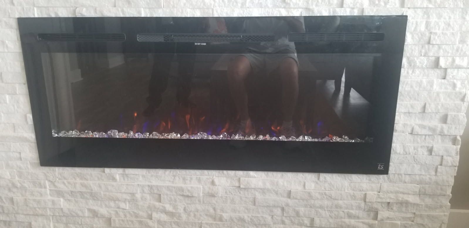 A black fireplace is hanging on a white brick wall.