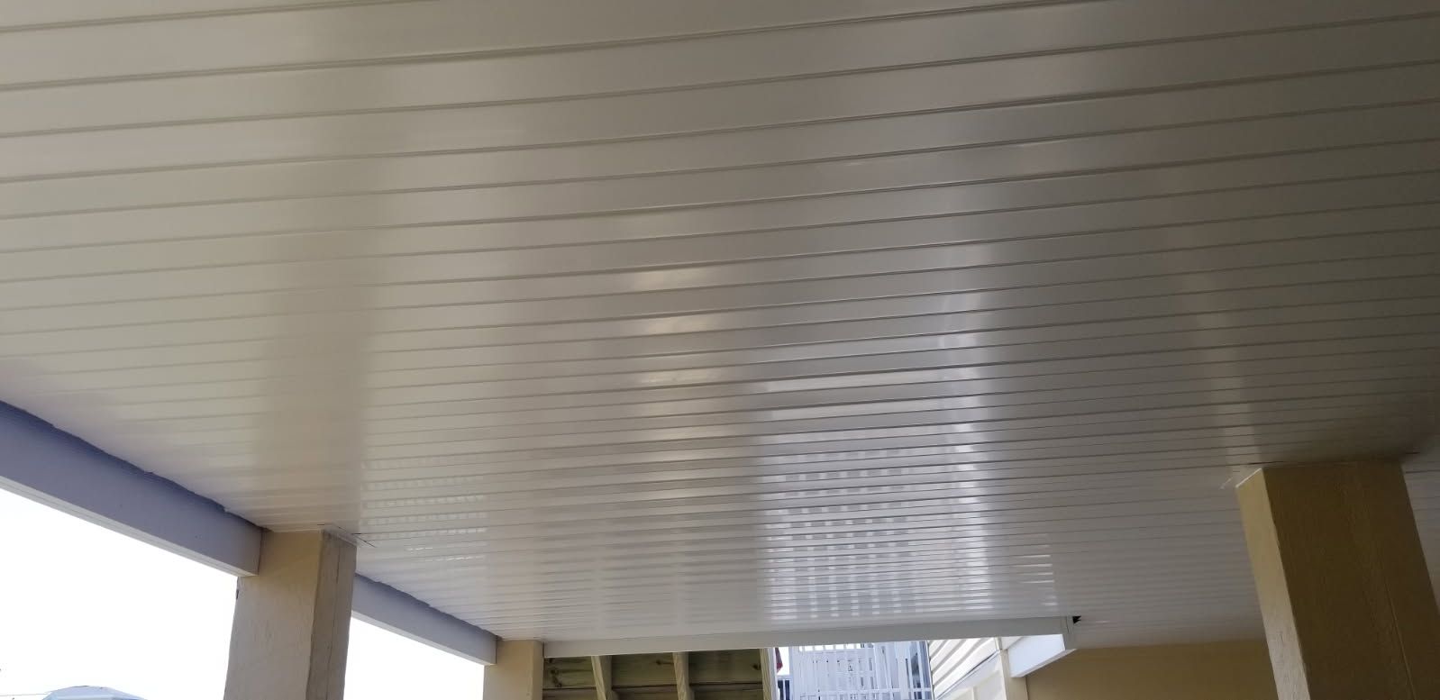 A white ceiling with a grid pattern is being installed on a porch.