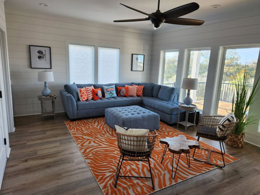 A living room with a blue sectional couch and an orange rug.