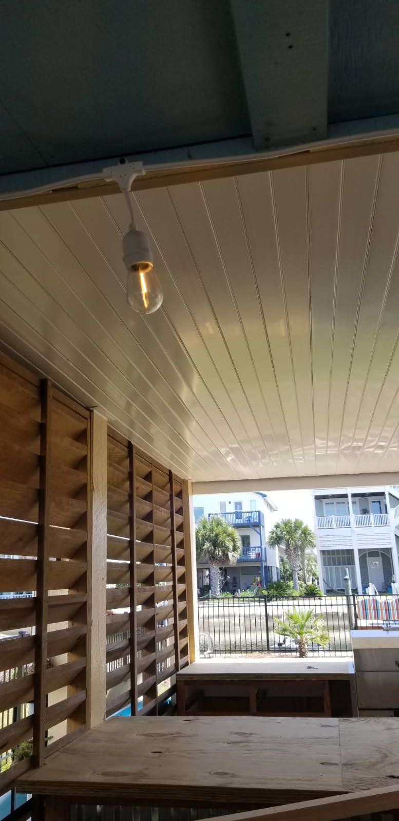 A light bulb is hanging from the ceiling of a porch.
