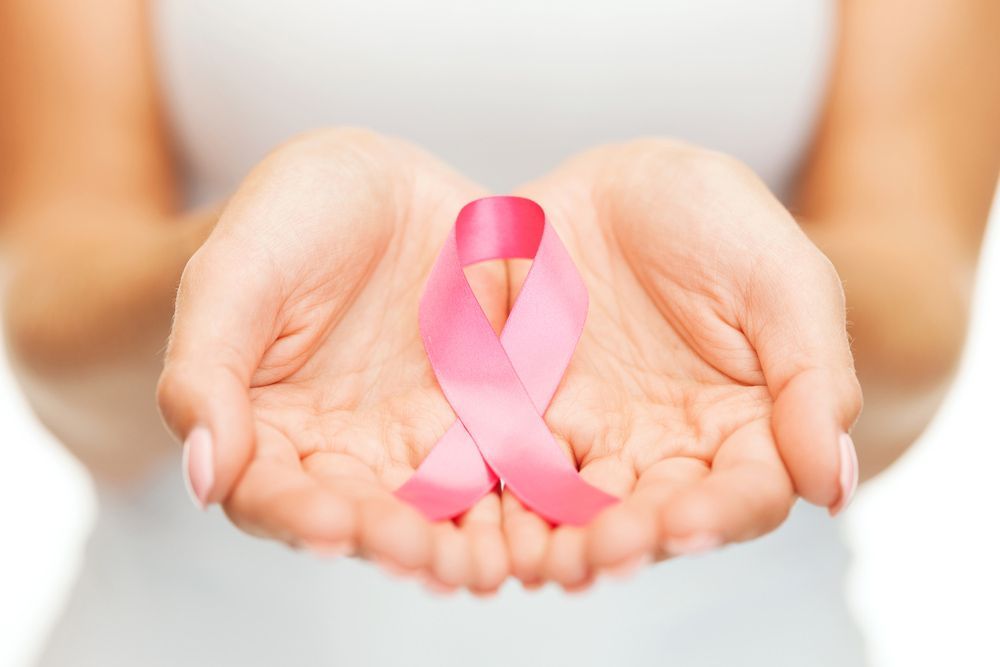 A Woman is Holding a Pink Ribbon in Her Hands — Northern Beaches GP Superclinic in Deeragun, QLD