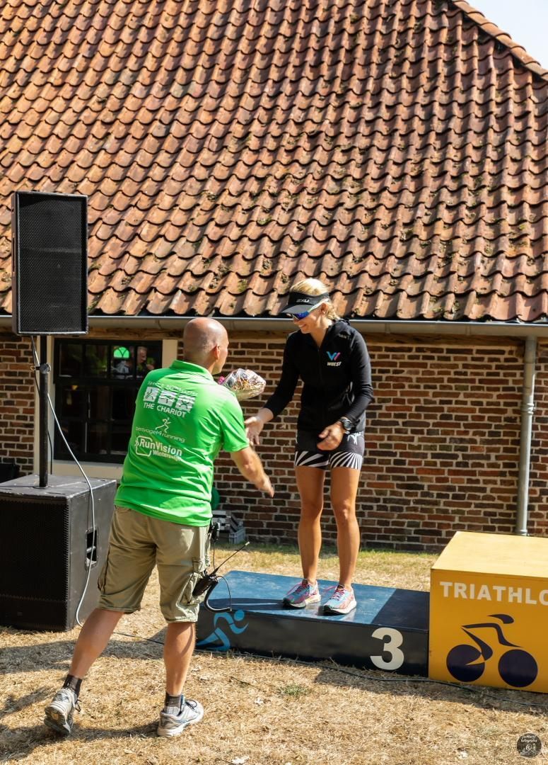 Een man in een groen shirt schudt de hand van een vrouw op een podium.