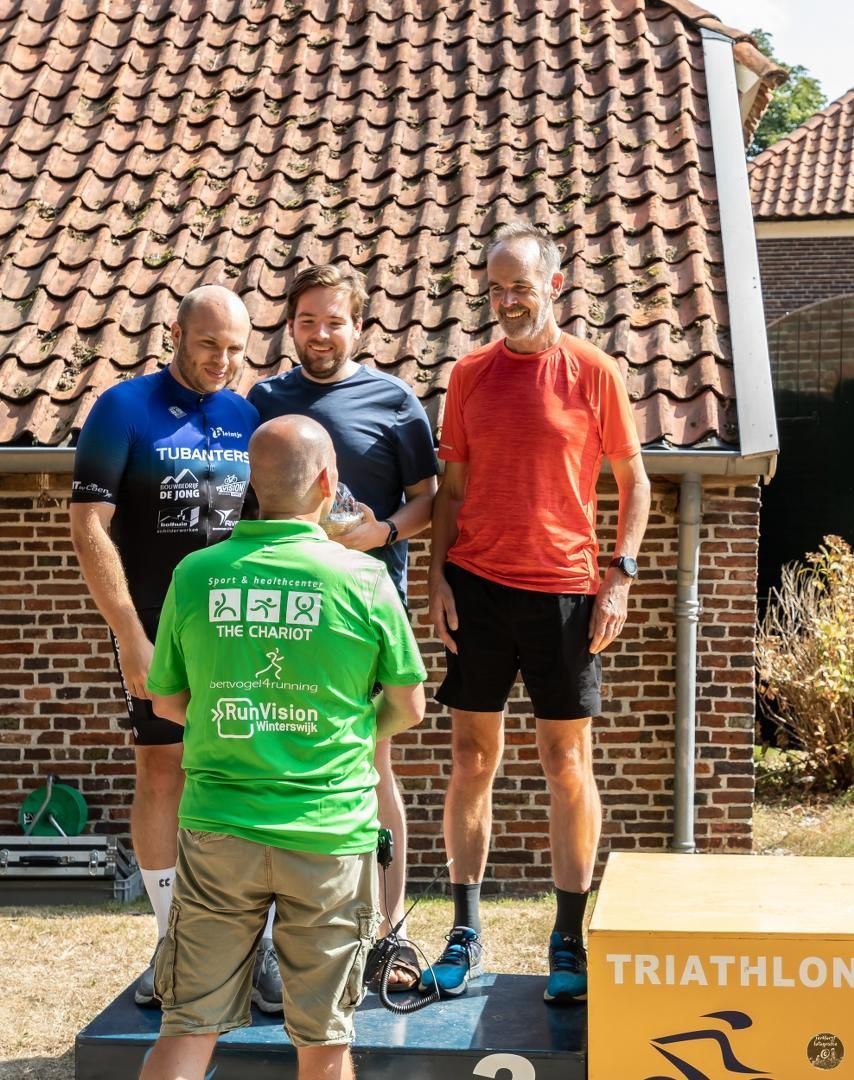 Een groep mannen staat op een podium tijdens een triatlon.