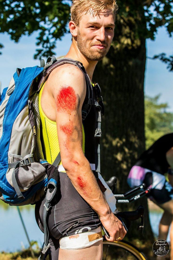 Een man met een rugzak staat naast een fiets.