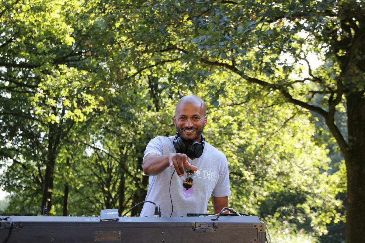 Een man met een koptelefoon speelt muziek in een park.