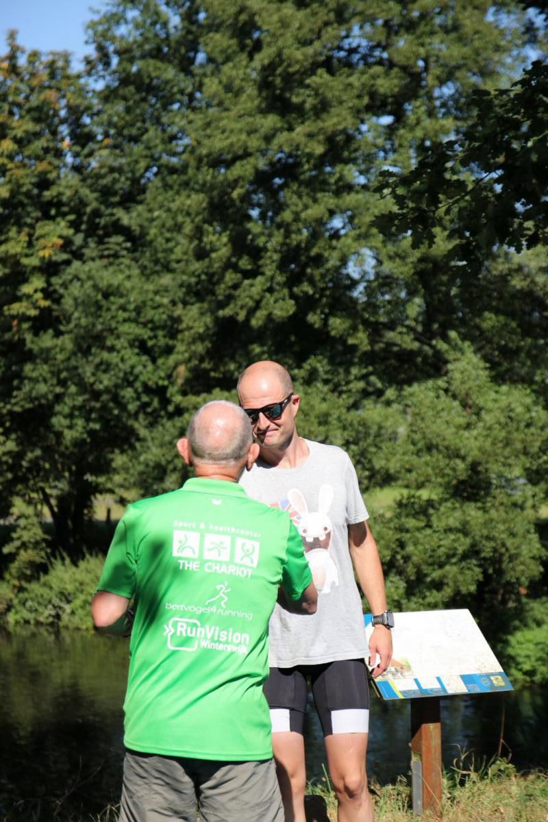Een man in een groen shirt schudt de hand van een andere man in een grijs shirt.