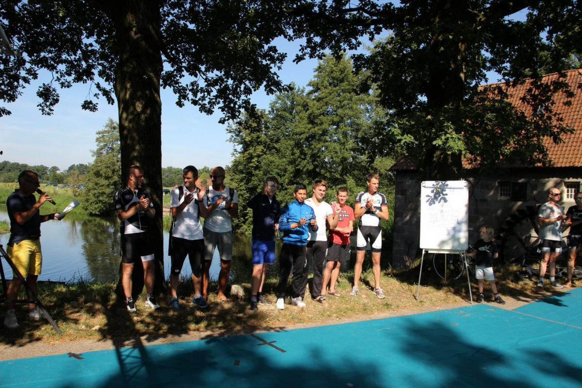 Een groep mensen die onder een boom staan ​​bij een watermassa
