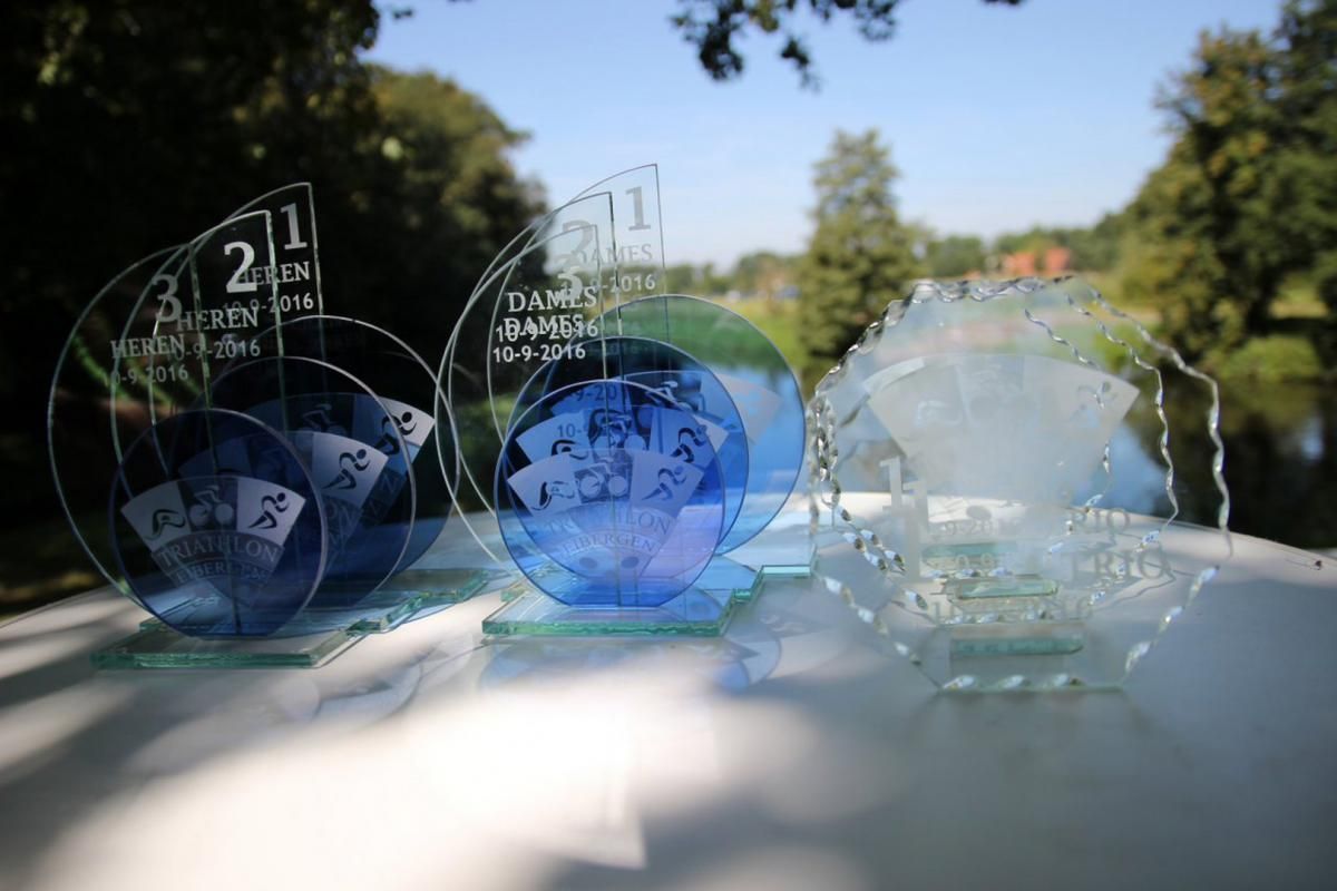 Drie trofeeën staan ​​op een tafel voor een rivier.