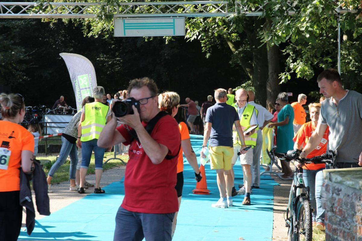 Een man in een rood shirt maakt een foto van een groep mensen