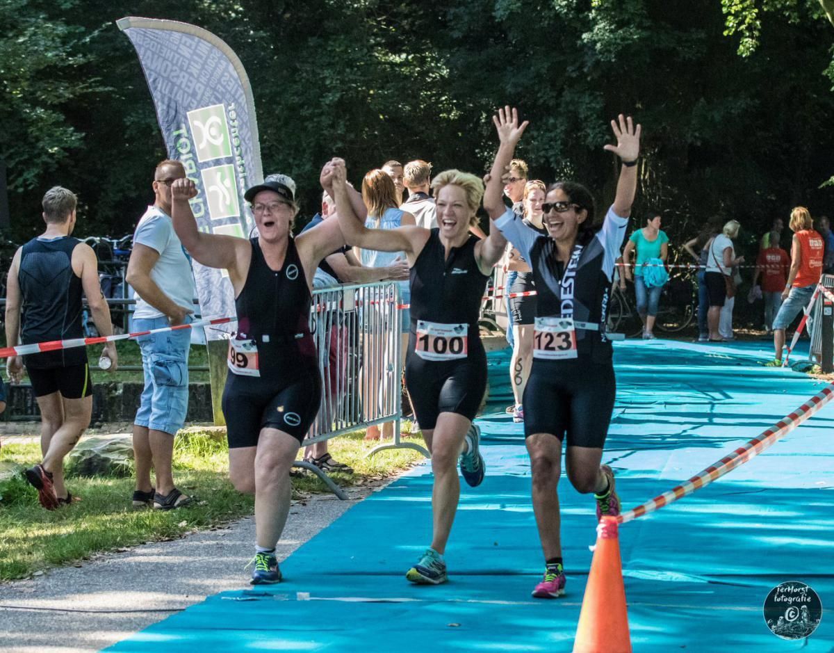 Een groep mensen doet mee aan een wedstrijd en een van hen heeft het nummer 100 op haar startnummer.
