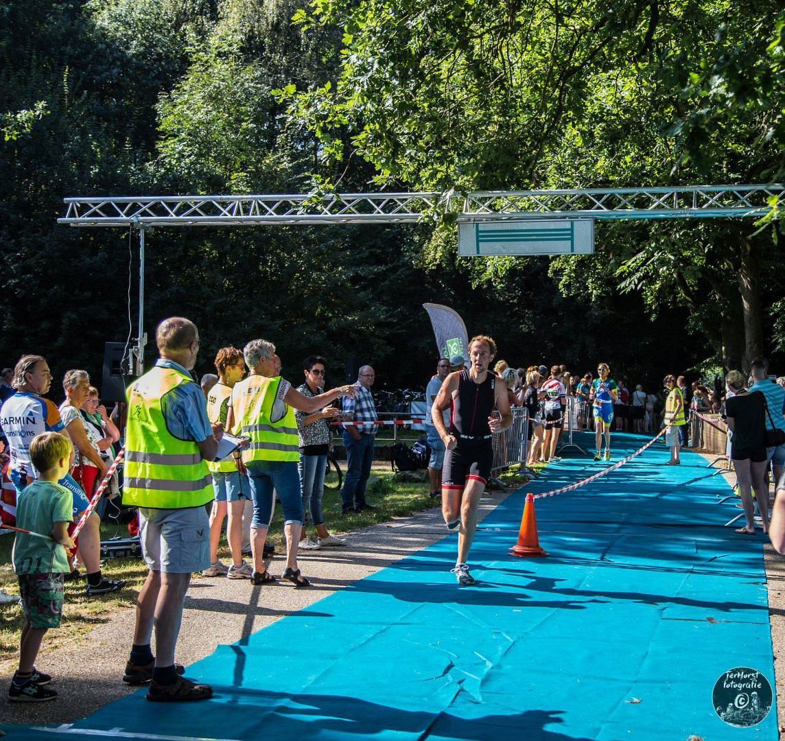 Een groep mensen kijkt naar een hardloper die de finishlijn passeert