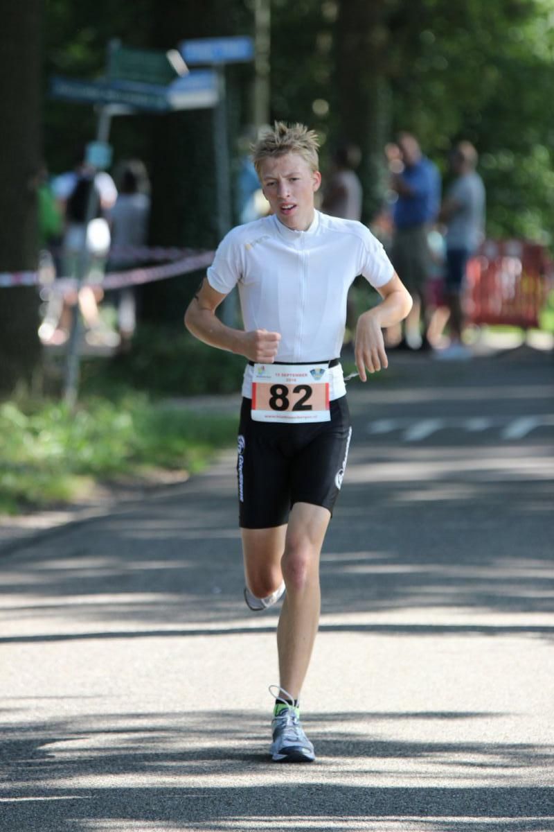 Een jongeman rent een marathon op de weg.