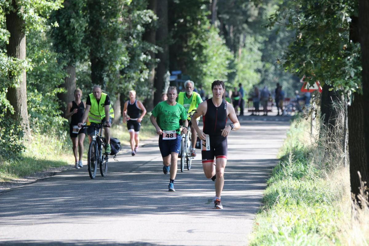 Een groep mensen rent en fietst over een weg.