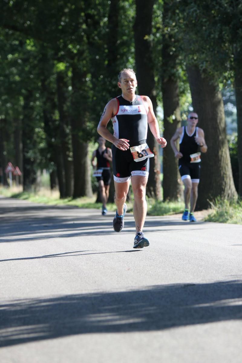 Een groep mensen rent over een weg met bomen op de achtergrond