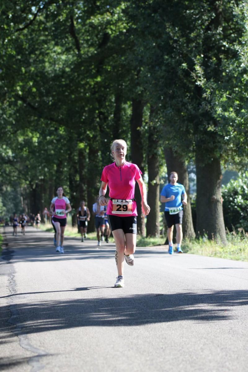 Een groep mensen rent over een weg met bomen op de achtergrond.