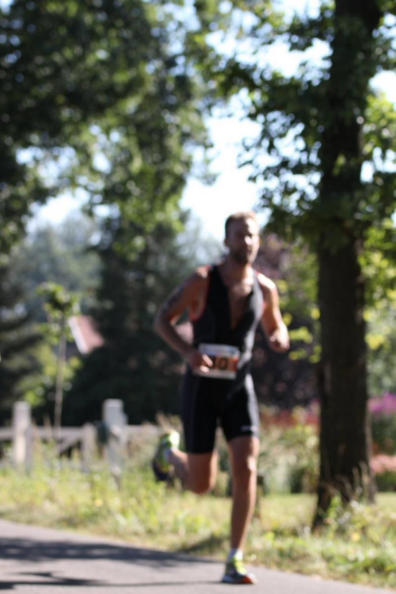 Een man rent op een pad met bomen op de achtergrond