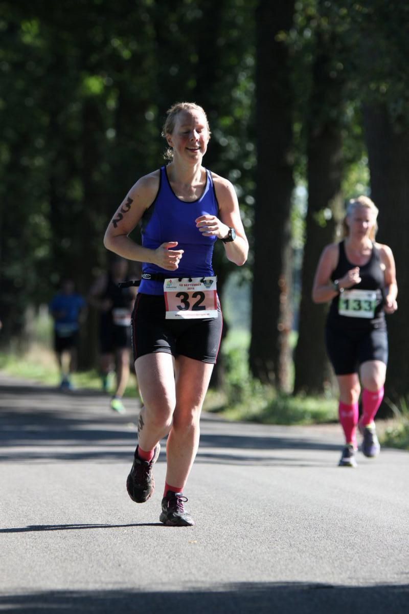 Een vrouw die een marathon loopt met het nummer 32 op haar riem
