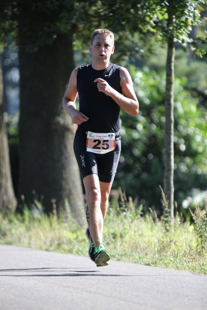 Een man rent over de weg met het nummer 25 op zijn riem.