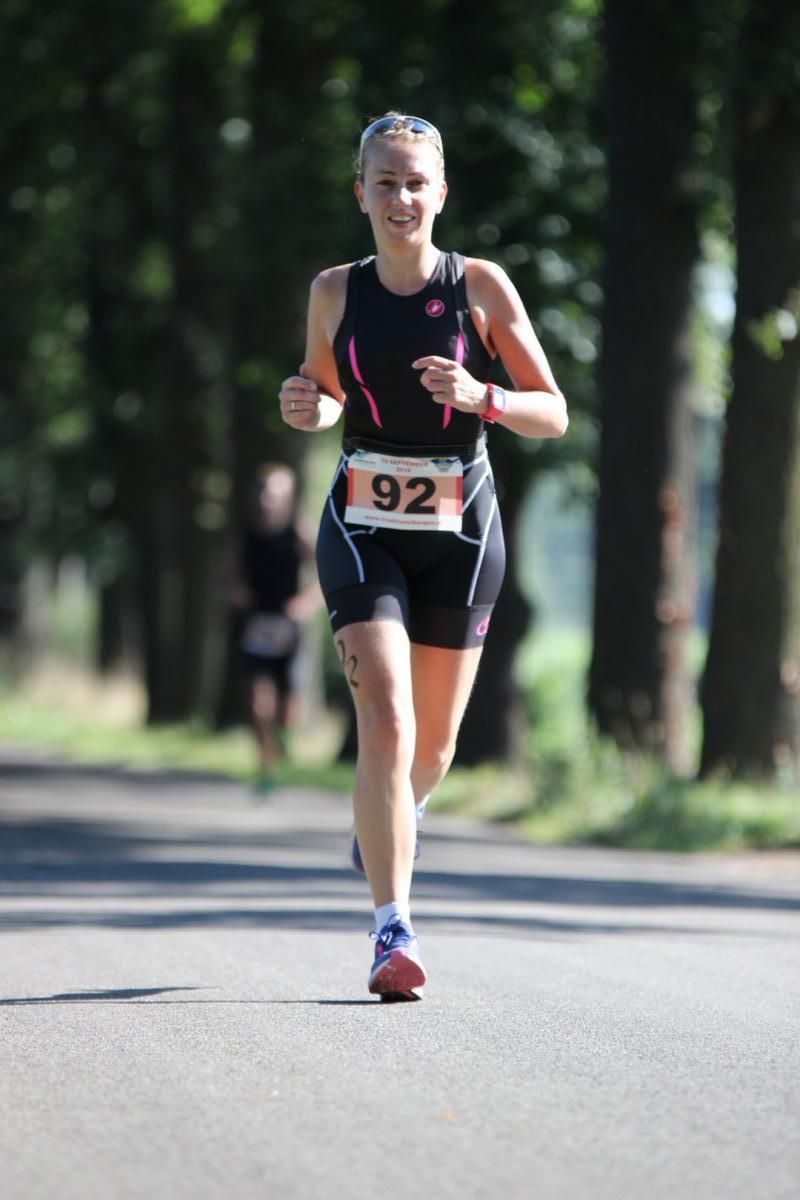 Een vrouw met rugnummer 92 rent over de weg.