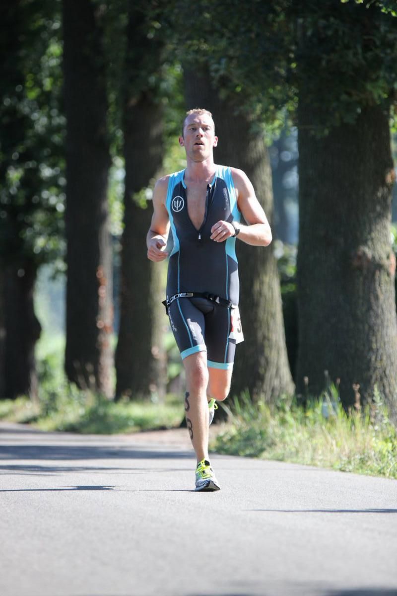 Een man rent over een weg met bomen op de achtergrond