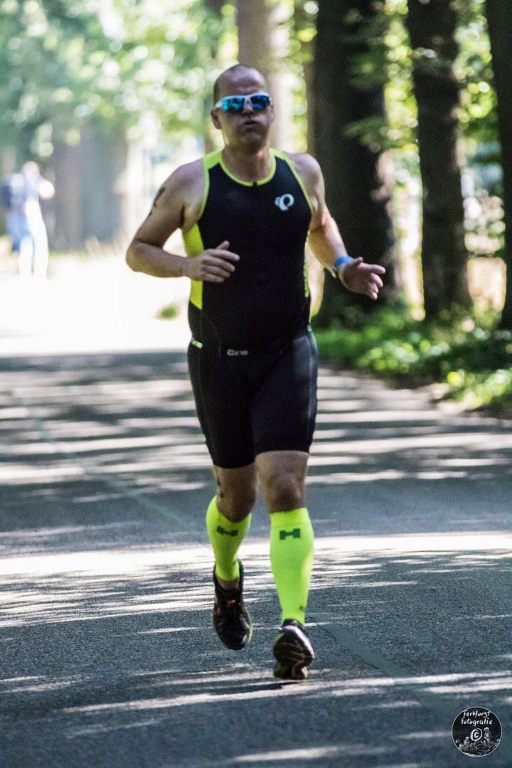 Een man met een zonnebril rent over de weg.