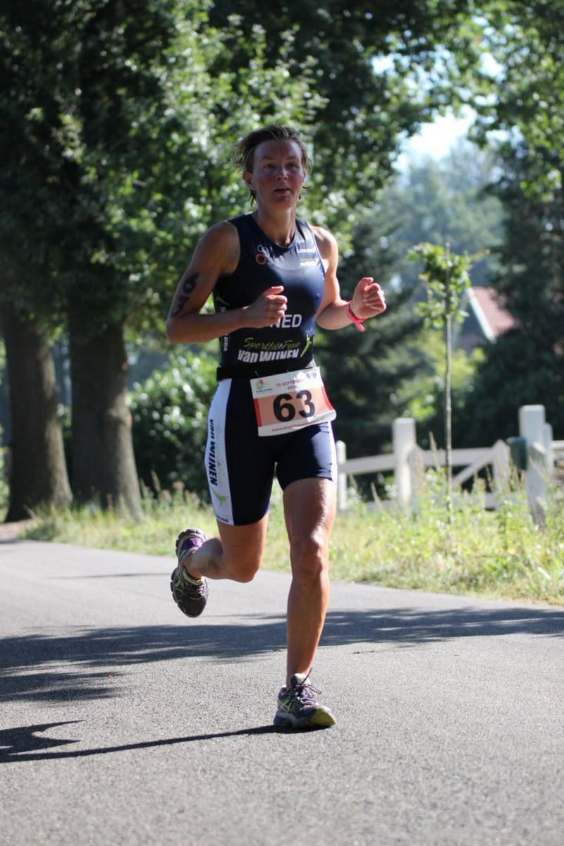 Een vrouw rent over de weg met een startnummer 63 om haar nek.