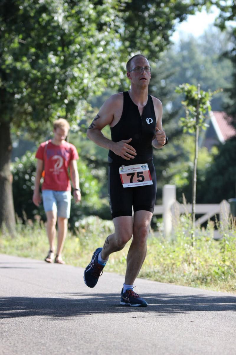 Een man rent over de weg met het nummer 75 op zijn shirt.