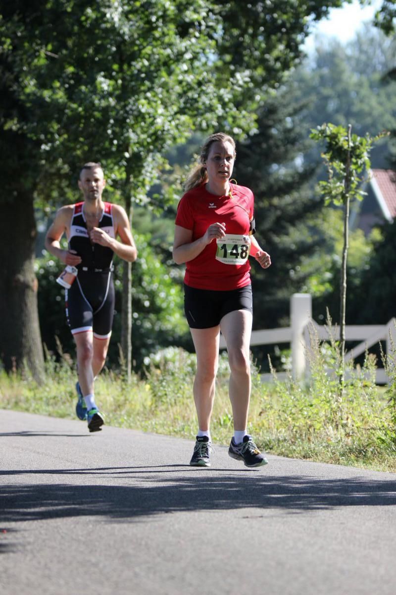 Een man en een vrouw rennen over de weg. De vrouw heeft het nummer 143 op haar shirt.