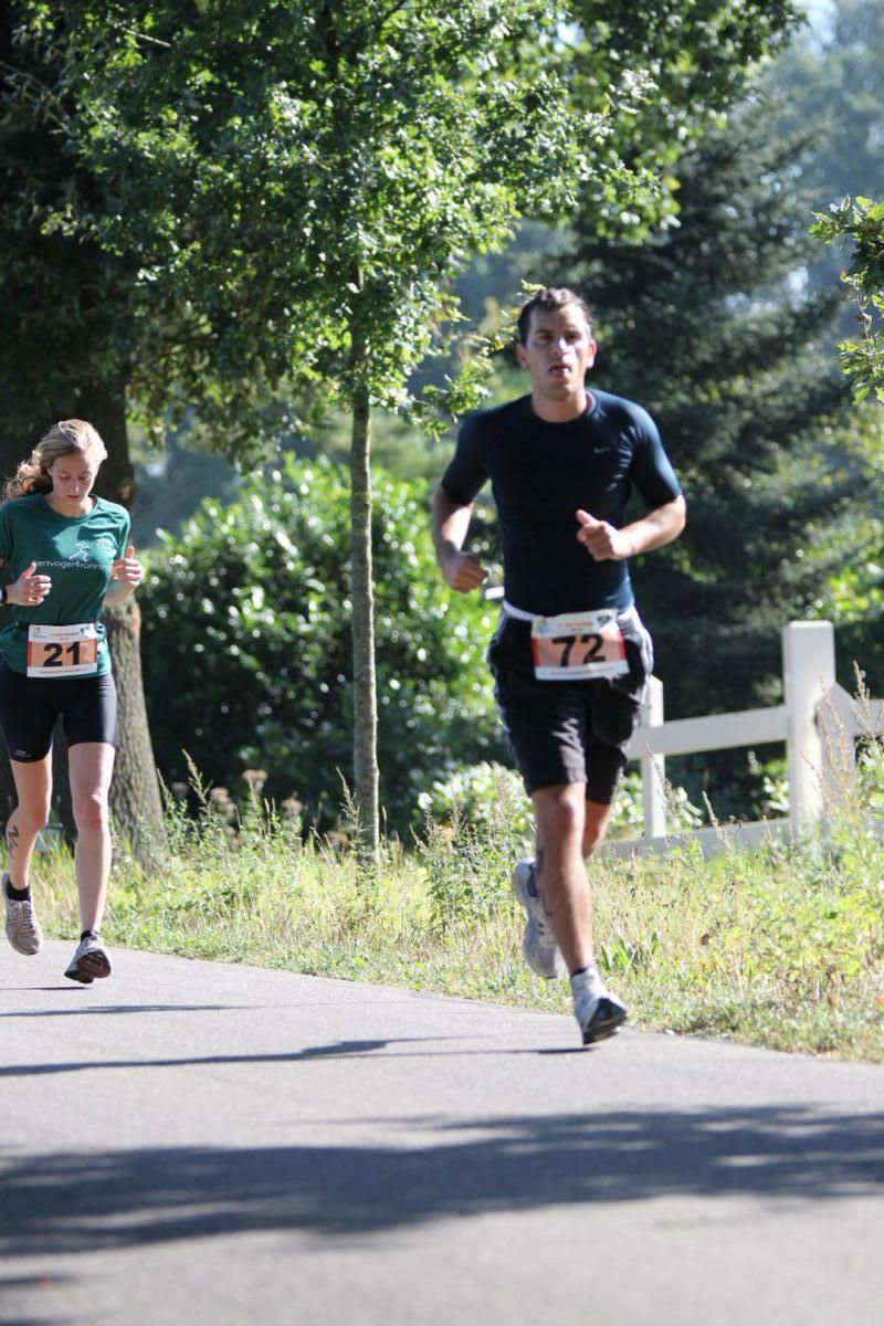 Een man en een vrouw rennen over de weg.