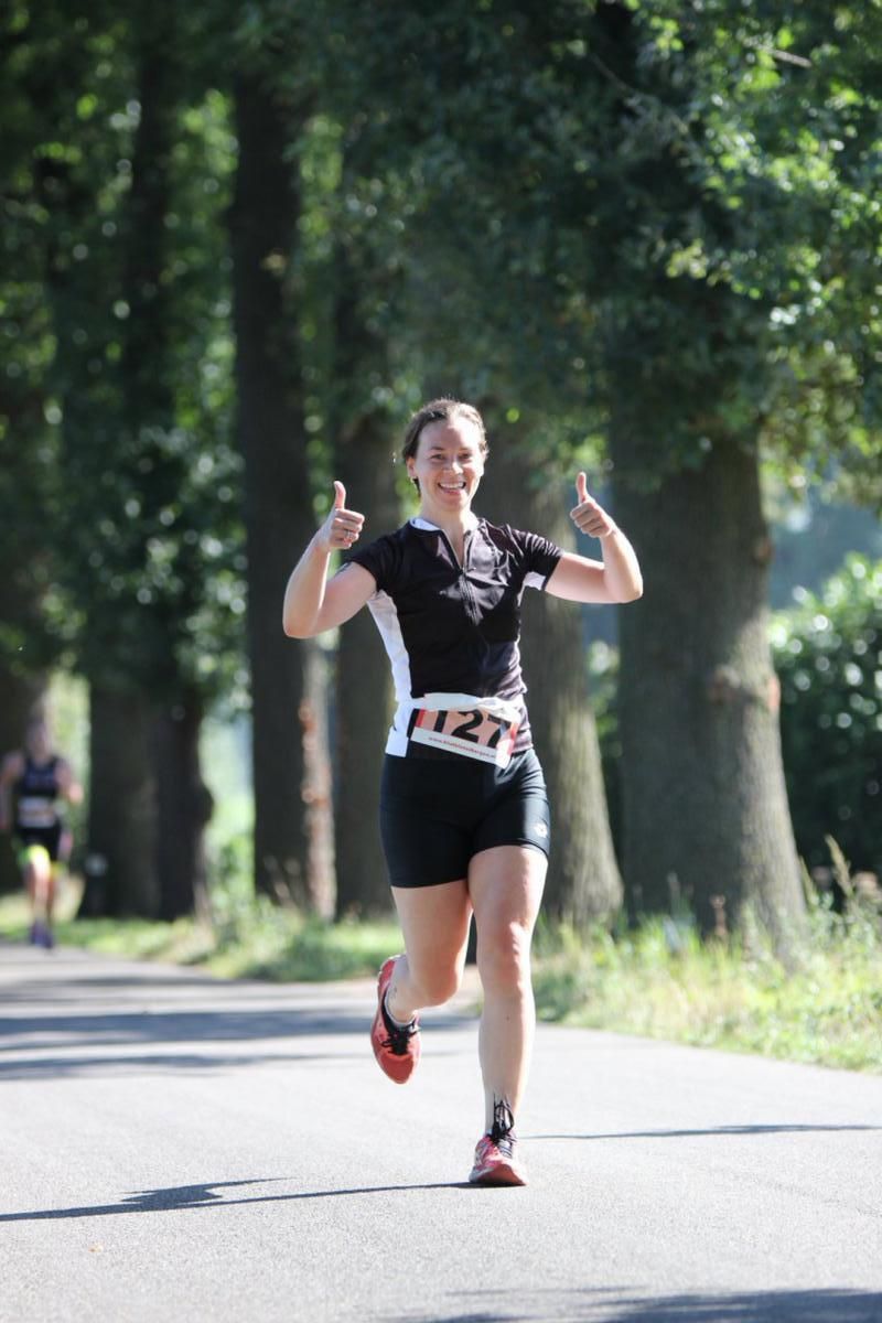 Een vrouw rent over de weg en steekt haar duim omhoog.