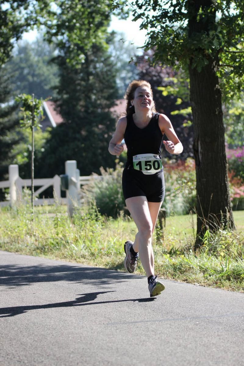 Een vrouw met startnummer 150 rent over de weg.