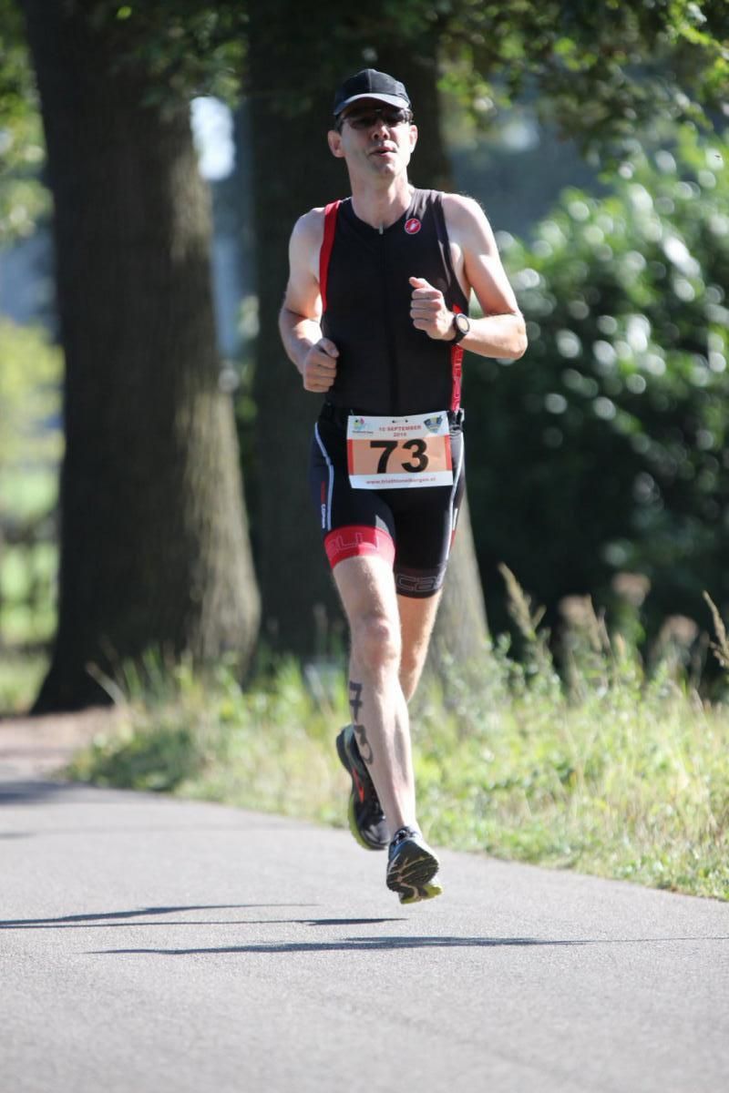 Een man die rent met het nummer 73 op zijn startnummer