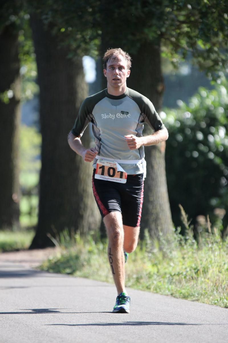 Een man met een startnummer 101 rent over de weg.