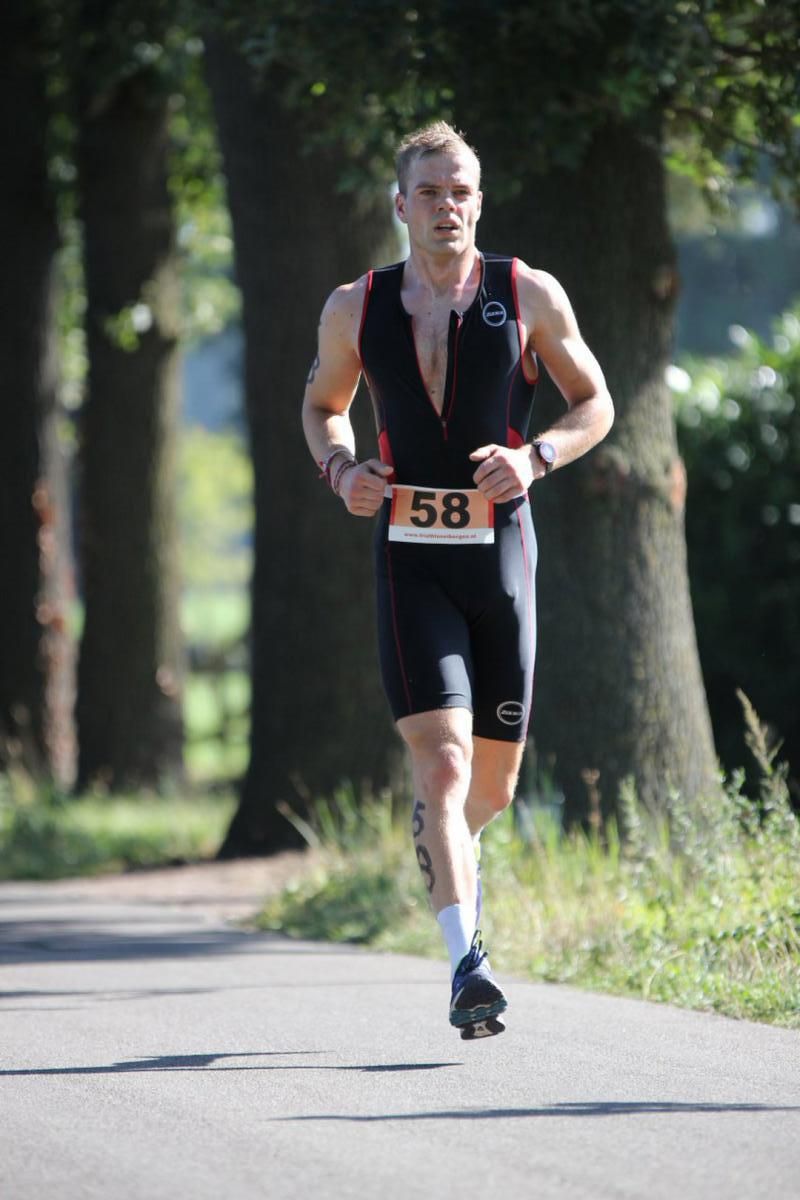 Een man rent over de weg met het nummer 58 om zijn middel.