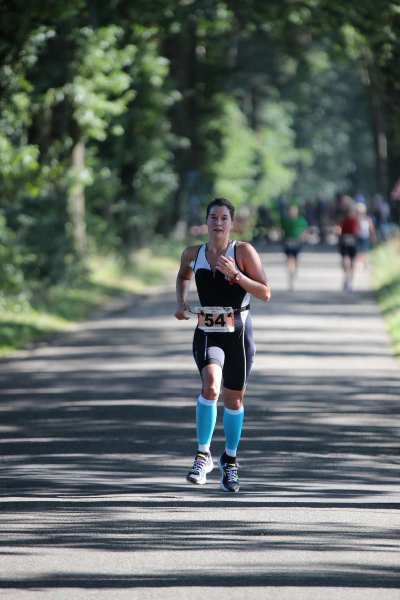 Een vrouw rent een marathon op de weg.