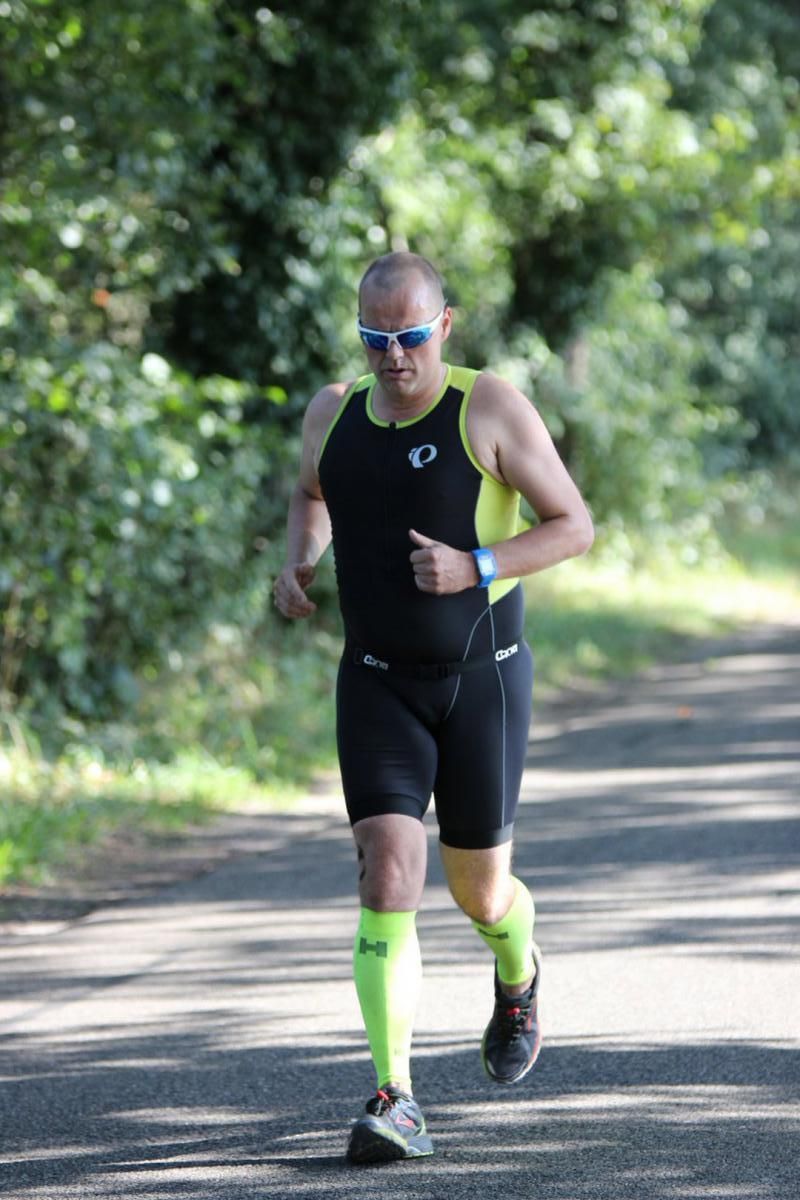 Een man rent over de weg met een zonnebril en neonkleurige sokken.
