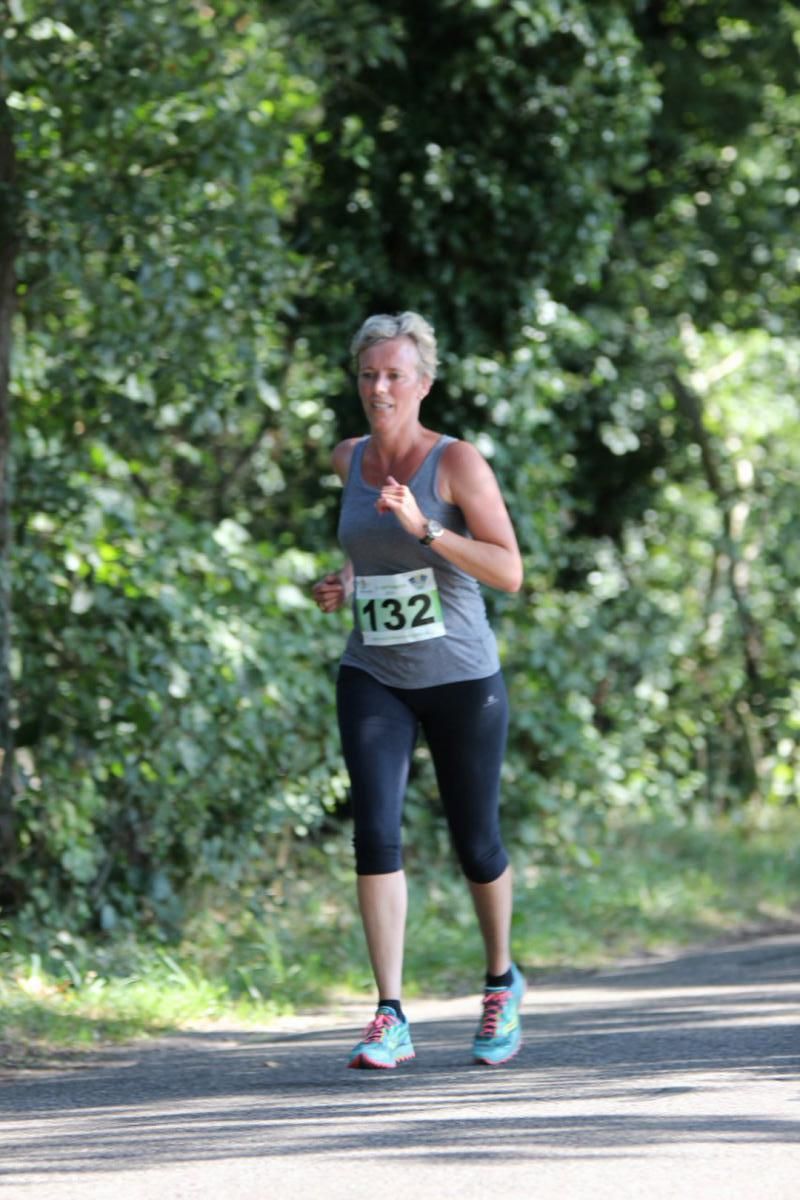 Een vrouw rent een race op een pad in het bos.