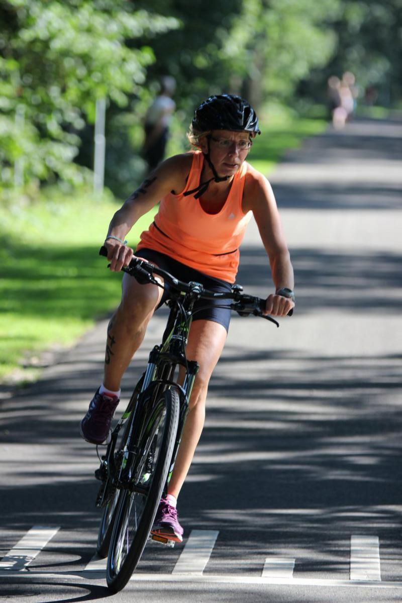 Een vrouw met een helm op fietst over de weg.