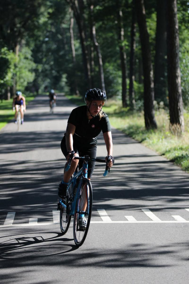 Een man met een helm rijdt op een fiets over een weg